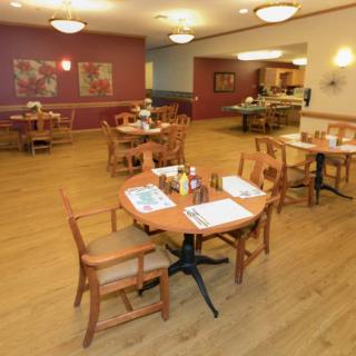 A warm and inviting restaurant dining area with wooden tables and chairs arranged neatly on a hardwood floor.