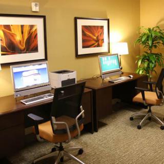 A modern office space with two workstations, featuring computers, chairs, and decorative artwork on the walls.