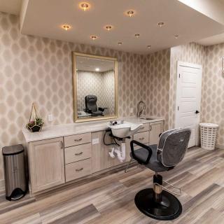 A modern salon interior with a hairdressing station, featuring a large mirror, comfortable chair, and sleek decor.