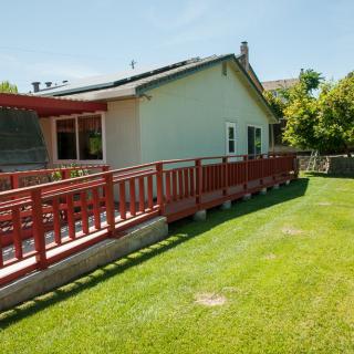 A sunny backyard view with a red wooden deck and a well-maintained lawn.