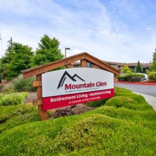 A sign for Mountain Glen Retirement Living and Assisted Living amidst well-maintained greenery and a clear blue sky.