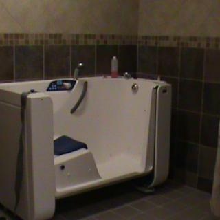 A walk-in bathtub in a tiled bathroom designed for accessibility.