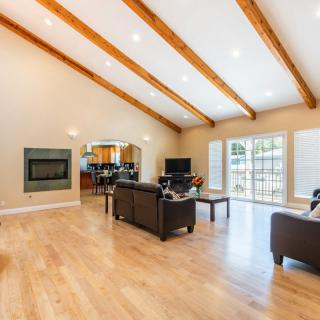 A spacious and bright living room featuring wooden beams, a vaulted ceiling, and comfortable seating.