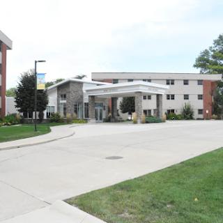 A modern building on a campus with a welcoming entrance and landscaped lawn.
