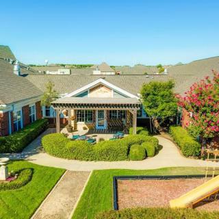 A well-maintained residential building with a landscaped garden and patio on a sunny day.