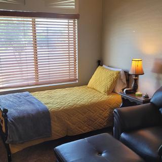 A cozy bedroom with a single bed, lamp, and comfortable seating.