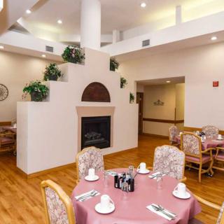 A cozy dining area with elegantly set tables and a decorative fireplace.