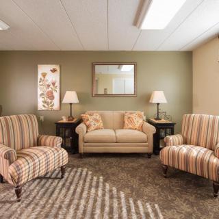 A cozy living room with striped armchairs, a sofa, and elegant lighting.