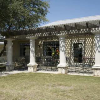 A house with a veranda featuring columns and shadow patterns on a sunny day.