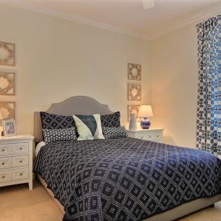 A cozy bedroom with a patterned bedspread and curtains, complemented by matching nightstands and lamps.