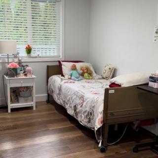 A cozy bedroom with a single bed and decorative items, featuring a window with blinds.