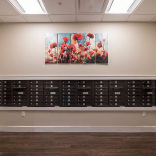 A hallway with rows of mailboxes below a vibrant floral artwork.