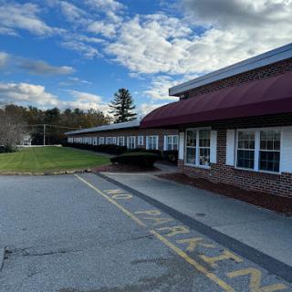 A view of a building with a parking lot under a cloudy sky.