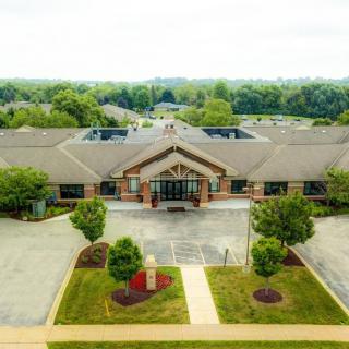Aerial view of a large building with surrounding parking lots and landscaped greenery.