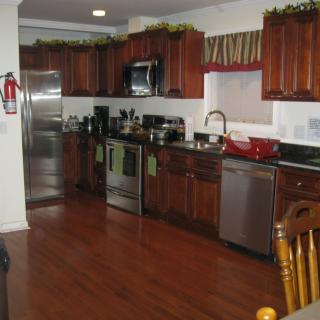 A modern kitchen with wooden cabinets and floors, featuring stainless steel appliances.