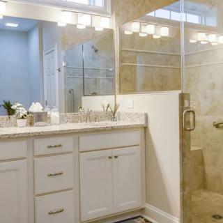 A modern bathroom with a white vanity, large mirror, and a glass-enclosed shower.