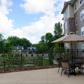 Outdoor patio area with a table, chairs, and umbrella next to an apartment building.
