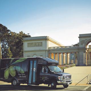 A truck parked in front of a monumental structure on a sunny day.