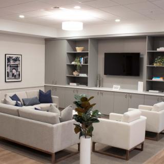 A modern living room featuring a comfortable seating arrangement, wall-mounted television, and decorative shelving.