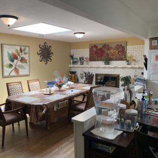 A cozy dining area with a table set, artwork on the walls, and a view into the kitchen.