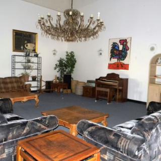 A spacious living room with a grand chandelier, multiple sofas, and a piano.
