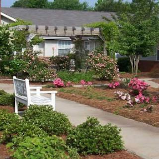 A serene garden area featuring vibrant flowers and a welcoming bench along a pathway.