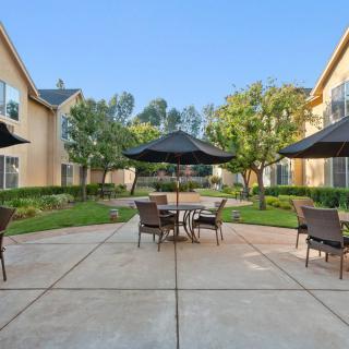 A tranquil apartment courtyard with patio furniture and large umbrellas.