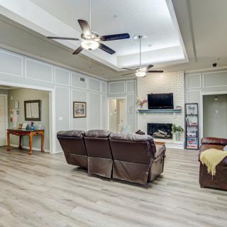 Spacious living room with a modern design featuring a comfortable sofa, ceiling fans, and a fireplace beneath a mounted television.