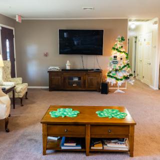 A cozy living room featuring a television mounted on the wall, a wooden coffee table adorned with decorations, and a beautifully decorated Christmas tree.