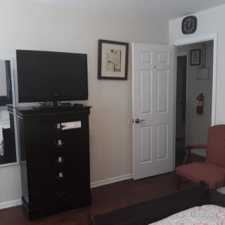 A bedroom with a dresser, television, and a chair near a doorway.