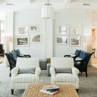 A stylish living room featuring comfortable chairs, a wooden coffee table, and framed artwork on the walls.