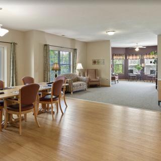 A spacious interior with a dining area and living room, featuring wooden floors and large windows.