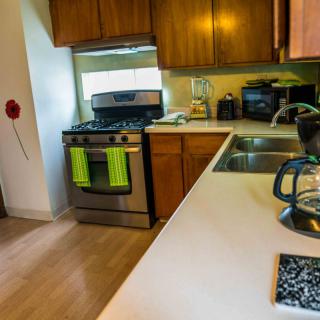 A modern kitchen with wooden cabinets, a stainless steel stove, and a double sink.