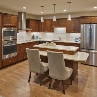 A modern kitchen with wood cabinets, a central island, and stainless steel appliances.