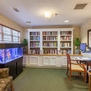 A cozy reading room with a large bookshelf and an aquarium.