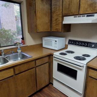 A compact kitchen with wooden cabinets, equipped with a stove, microwave, and sink.