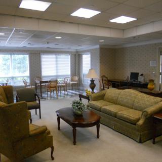 A cozy living room featuring sofas, armchairs, and a coffee table with ample window lighting.