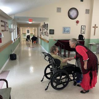 A caregiver interacts warmly with an elderly resident in a nursing home corridor, highlighting the importance of personal connections in elder care.