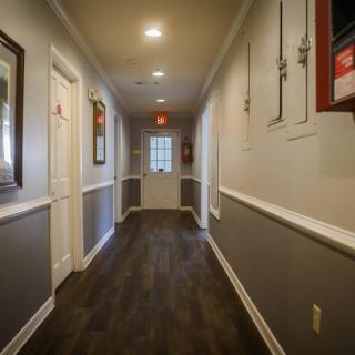 A well-lit hallway with dark flooring and decorated walls.