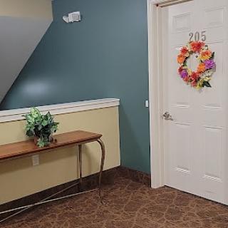A cozy hallway featuring a welcoming door adorned with a colorful wreath and a small table with a plant.