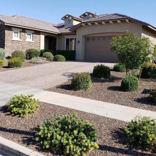 A well-maintained suburban house with a neatly landscaped front yard and driveway on a sunny day.