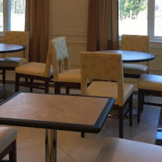 A cozy seating area featuring tables and chairs, illuminated by natural light from nearby windows.