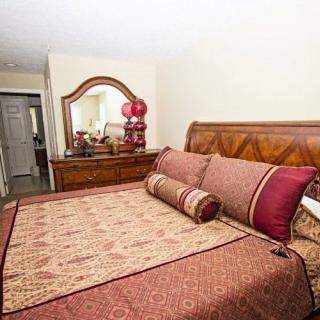A neatly arranged bedroom featuring a bed with decorative pillows and a wooden dresser with a mirror.