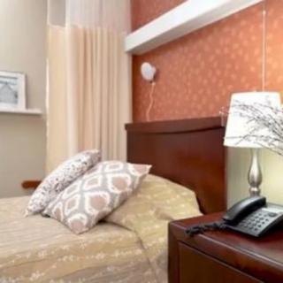 A cozy bedroom featuring a bed with patterned pillows, a lamp on a nightstand, and warm decor.