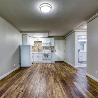 A spacious, modern kitchen area with wooden flooring and white cabinetry.