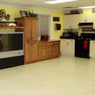 A kitchen interior with cabinetry, appliances, and a television against yellow walls.