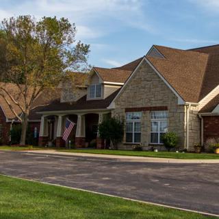 A suburban house with a well-maintained lawn and driveway on a clear day.