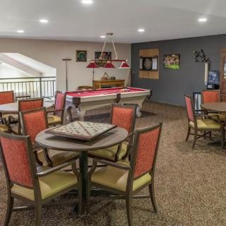 A well-furnished game room featuring a pool table and multiple tables with chairs for social gatherings.