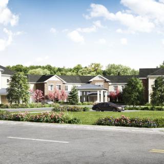 A scenic view of a large residential building with a landscaped frontage and road.