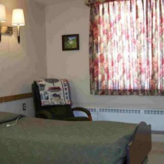 A cozy bedroom with a bed, chair, and floral curtains.